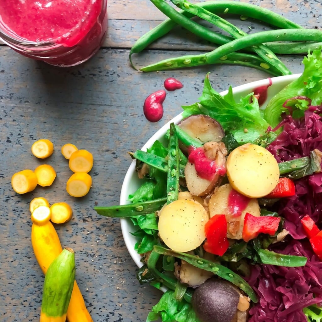 A close up of a bright and vibrant farmer's market salad with a beet vinaigrette.