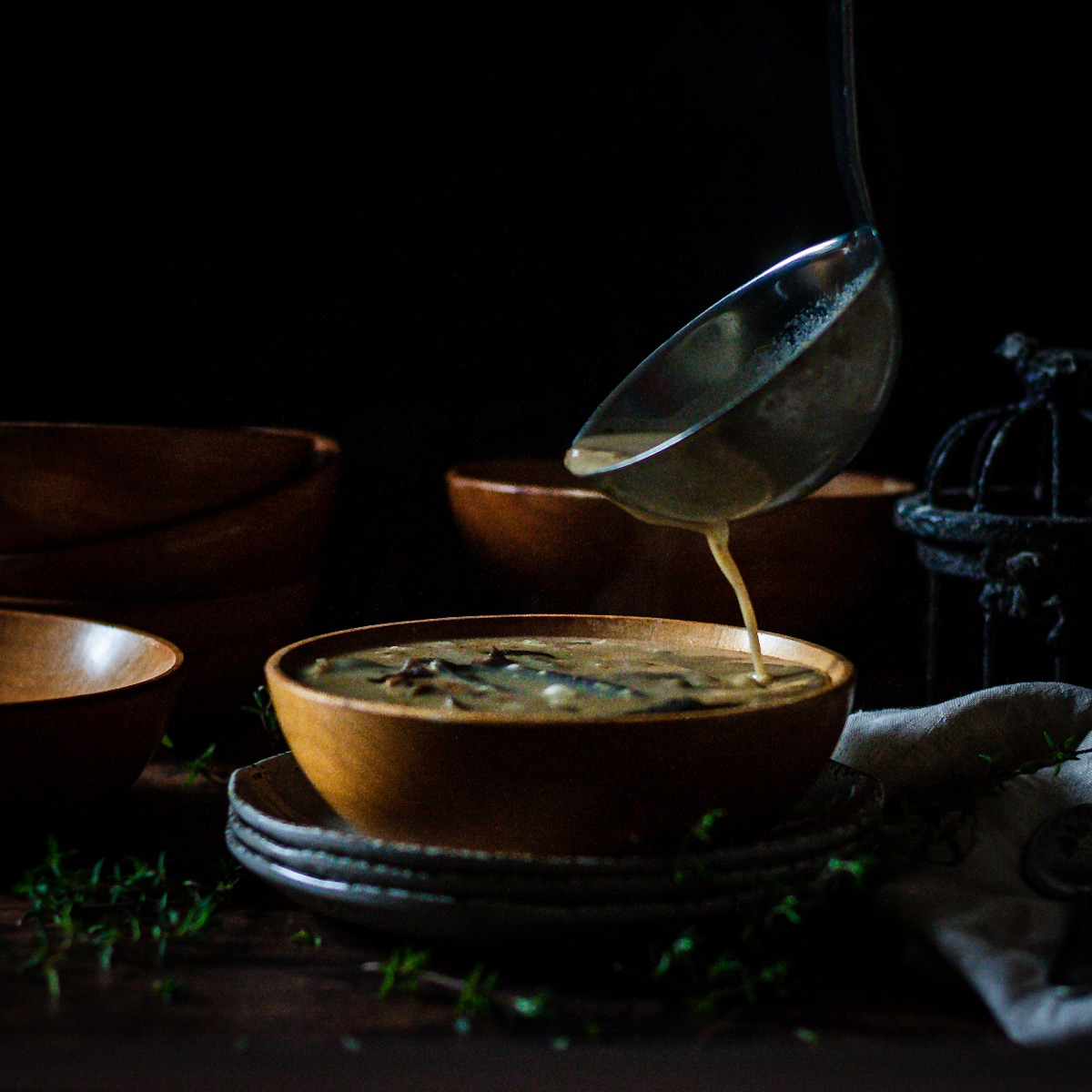 Creamy wild mushroom soup being poured into a bowl.