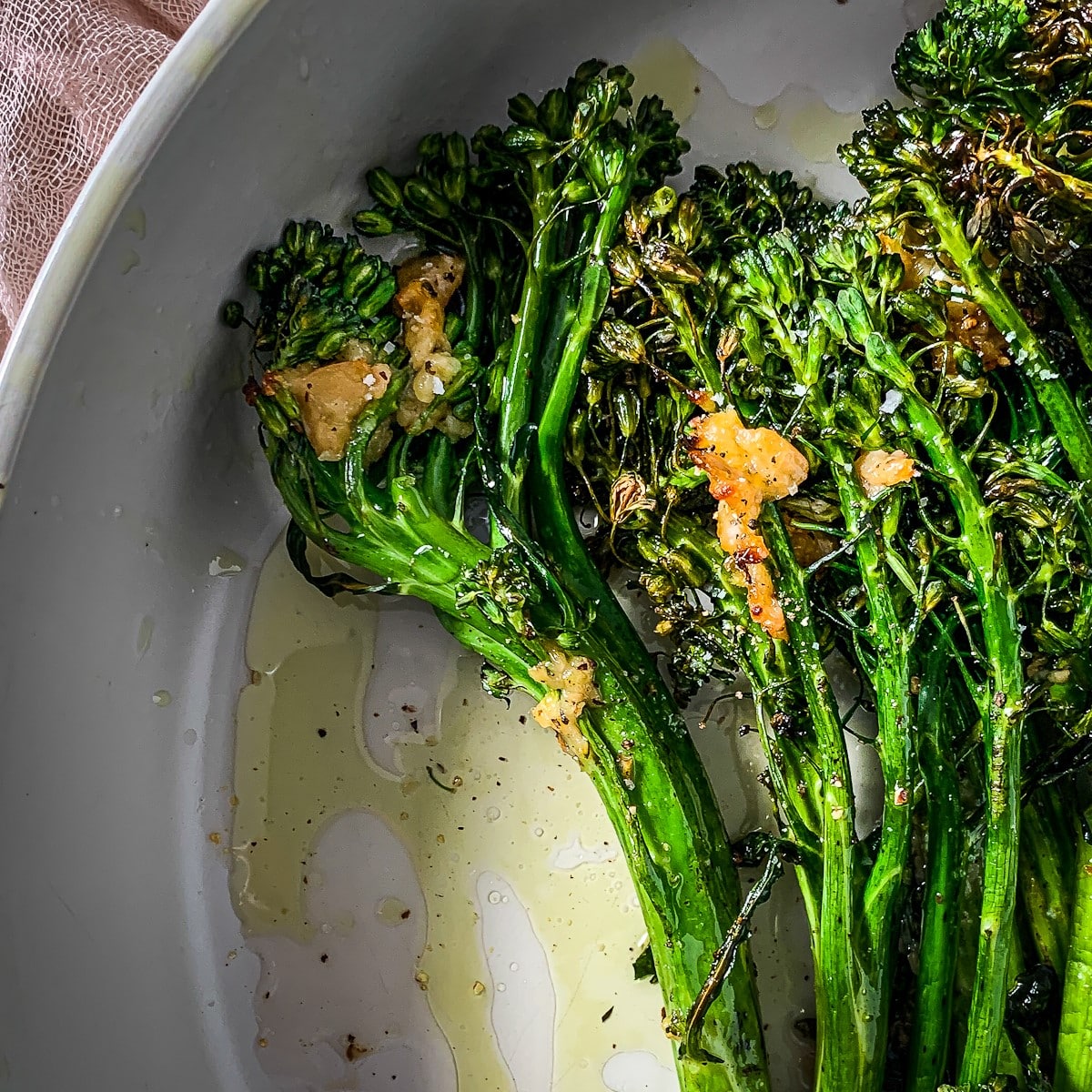 closeup of roasted tenderstem broccoli  (broccolini) in a serving dish.