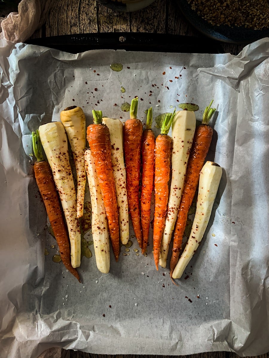 Overhead view of carrots and parsnips prepared with honey for roasting..