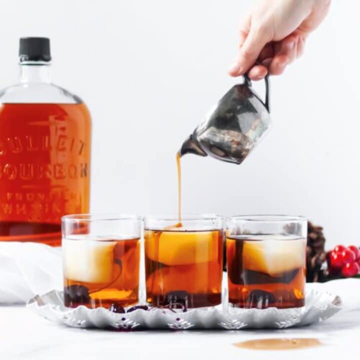 Maple syrup poured into a maple bourbon cocktail