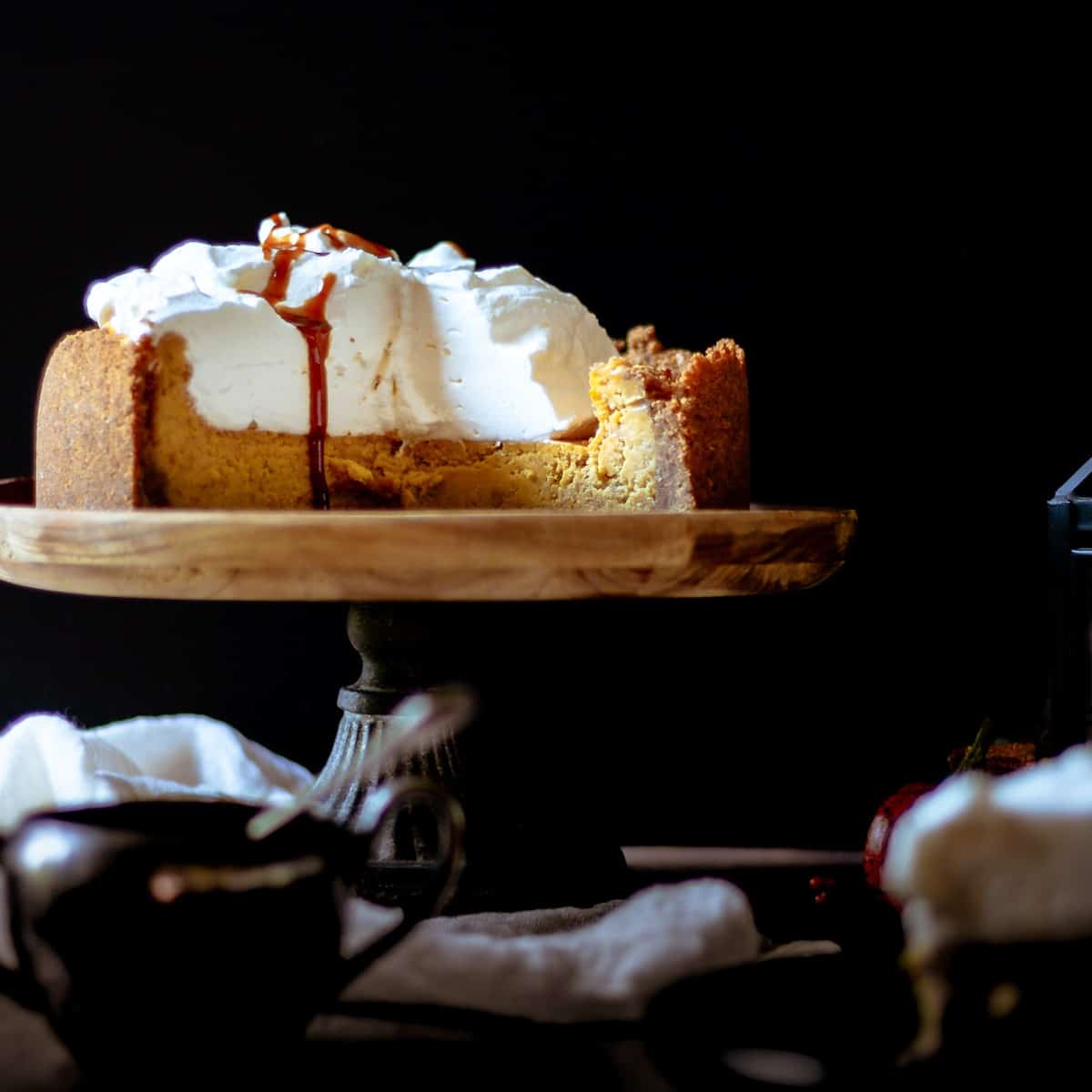 Straight view of a sliced whole pumpkin cheesecake with gingerbread caramel sauce drizzle.