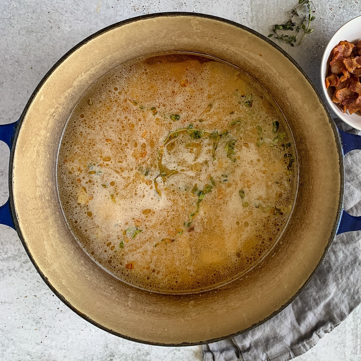 Stock simmering in a soup pot with thyme, onions, garlic and celery.