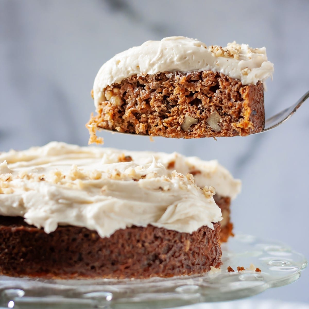 Slice of carrot walnut cakes on a spatula served out of a whole cake.