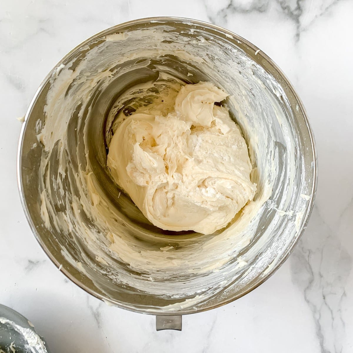 Whipped cream cheese frosting in a metal bowl.