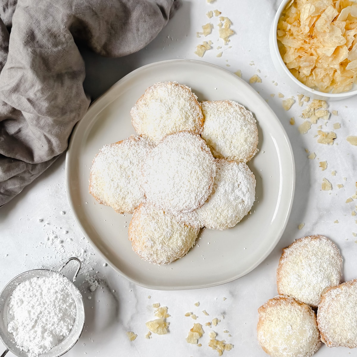 overhead shot of potato chip cookies on a plate with powdered sugar on the side and potato chips on side.