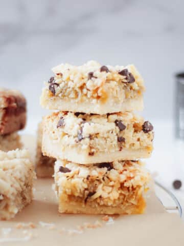 Chocolate coconut bars stacked with chocolate chips scattered around.